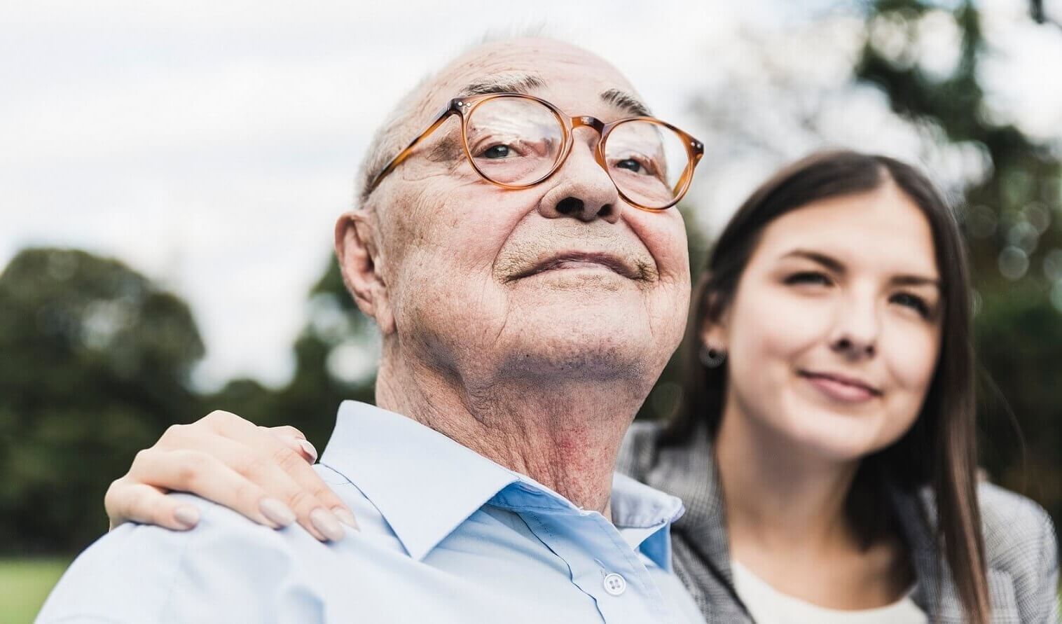 Vieil homme avec lunettes, regarde fièrement devant lui, jeune femme à ses côtés
