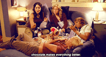 Filles en pyjama, mangent du chocolat sur un canapé