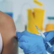 Bras de femme, gros plan sur gants bleus qui tiennent une seringue de vaccin