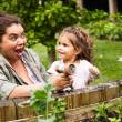 Femme et petite fille rigolent avec tuyau d'arrosage, arrosent des plantes vertes