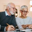 Un senior et sa femme complètent des documents administratifs dans leur domicile