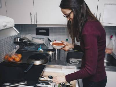 Jeune femme cuisine dans une kitchenette