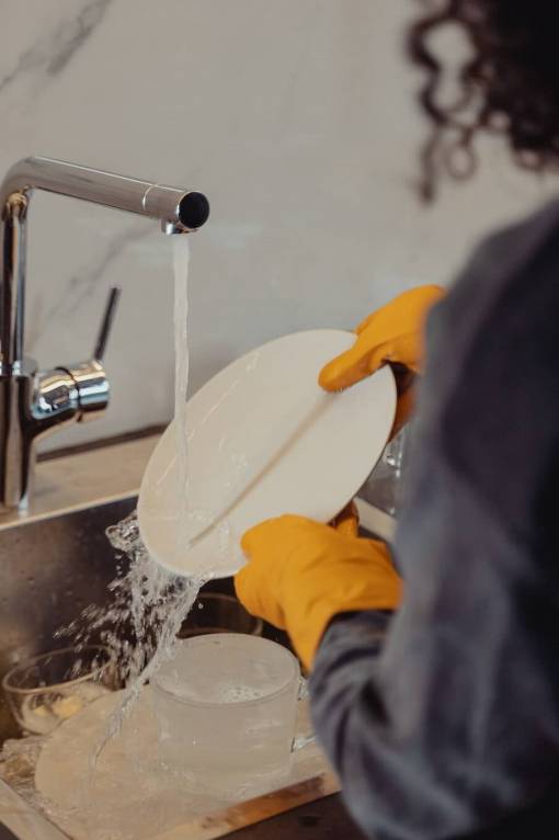 femme de dos, lave la vaisselle avec gants jaunes, eau qui coule - ©Tima Miroshnichenko, Pexels