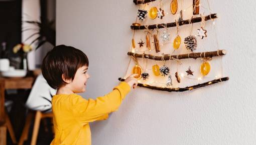 Enfant devant des batons et décorations accrochées au mur en forme de triangle