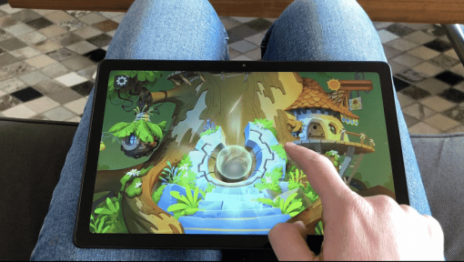 une tablette est posée sur les genoux avec un extrait du jeu