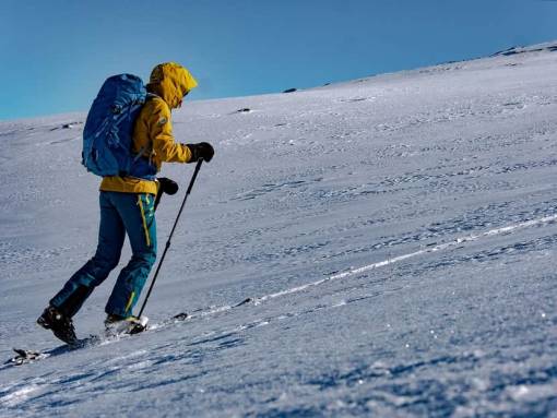 Une personne gravit une pente enneigée en ski de randonnée