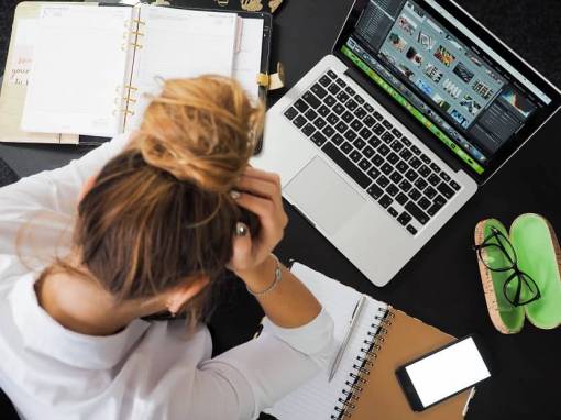 Une salariée est stressée et se tient la tête devant son ordinateur de travail