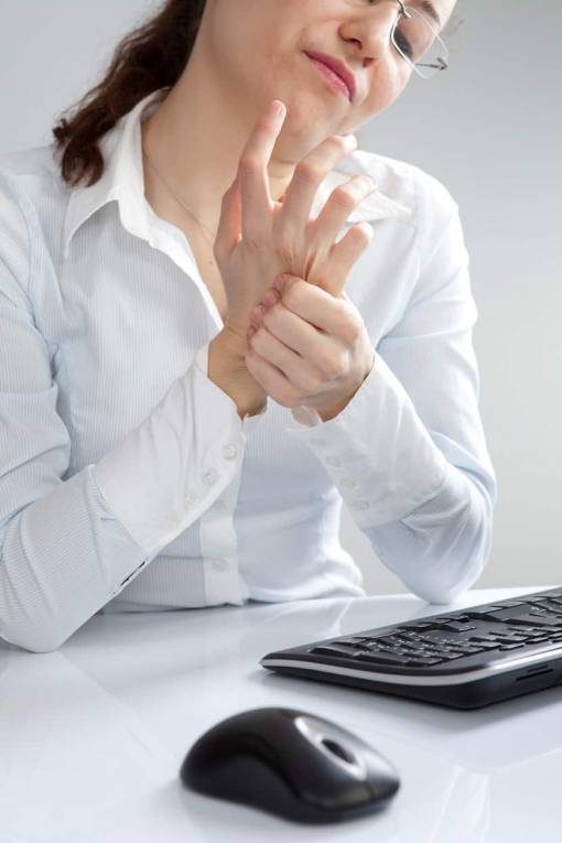 Une femme s'échauffe les poignets avant de travailler à son bureau