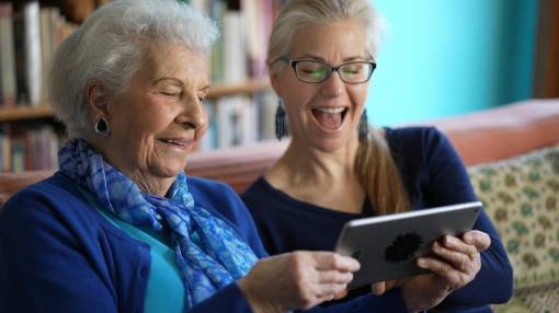 2 seniors rigolent et regardent ensemble une tablette numérique