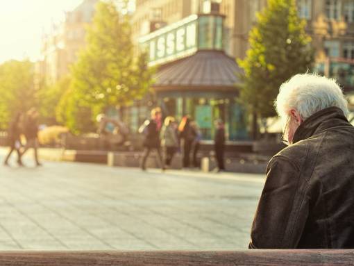 Homme seul assis sur un banc dans la rue, regarde par terre