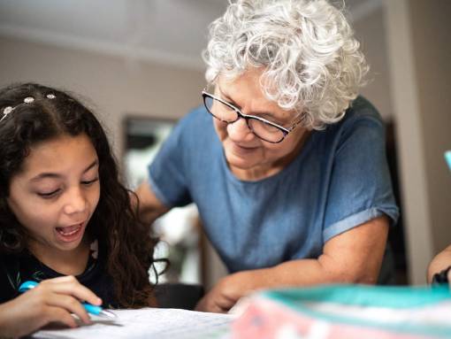 Personne âgée en train d'aider une fille avec ses devoirs