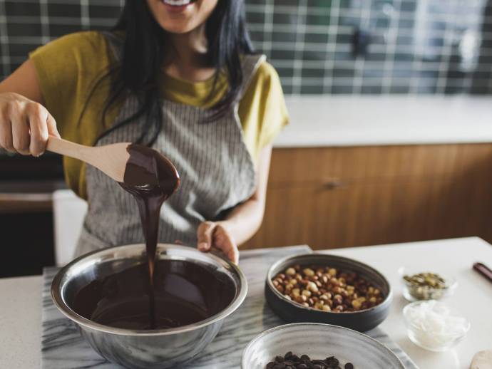 Femme souriante, tablier de cuisine, mélange chocolat fondu avec une cuiller en bois