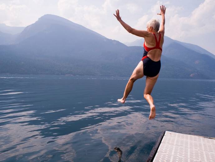 Femme âge mur, saute dans un lac en maillot rouge