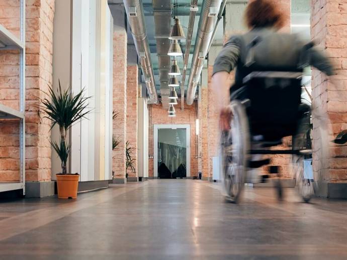 Femme en fauteuil roulant, couloir d'entreprise