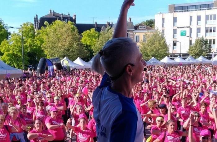 Foulées de la cathédrale de Chartres - Femme en tenue de sport qui brandit le bras, centaines de femmes avec T-shirts roses