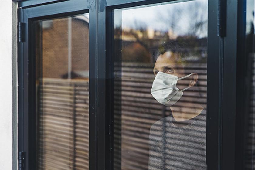 Un monsieur avec un masque qui regarde par la fenêtre