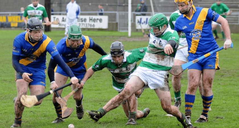 Joueurs de hurling, avec casques, maillots et bâtons plats sur terrain avec de l'herbe