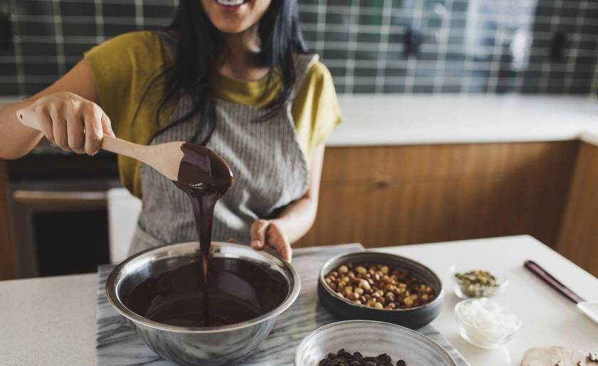 Femme souriante, tablier de cuisine, mélange chocolat fondu avec une cuiller en bois