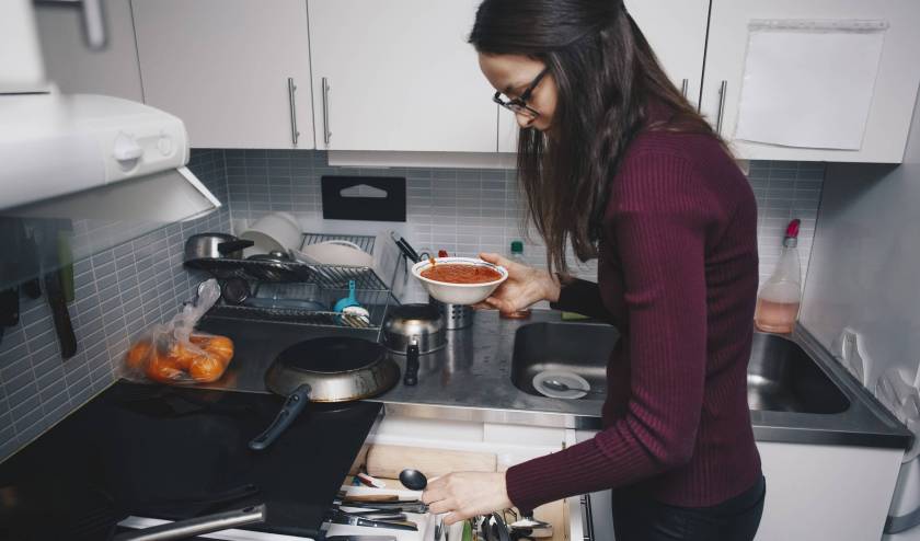 Jeune femme cuisine dans une kitchenette