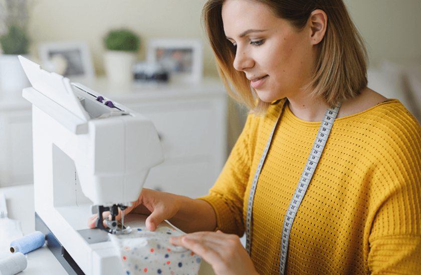 jeune femme en pull jaune, fais un masque en tissu à la machine à coudre