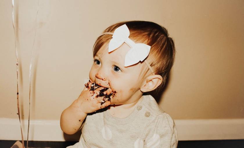 Petite fille avec nœud dans les cheveux, chocolat sur la bouche