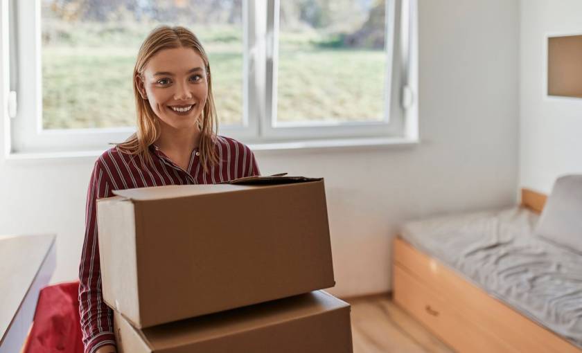 jeune femme avec des cartons de déménagement, chambre avec un lit simple