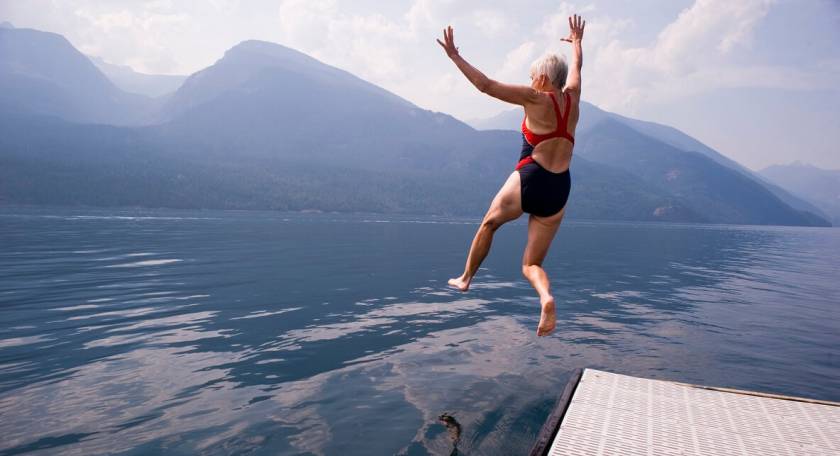 Femme âge mur, saute dans un lac en maillot rouge