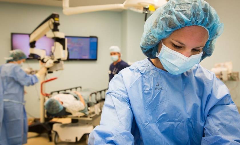 Femme en tenue de bloc d'hôpital bleu. En arrière plan, personne sur un lit