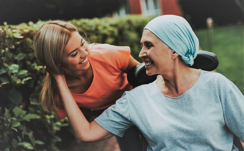 Femme avec un turban sur la tête, assise dans une chaise, sourit à une jeune femme