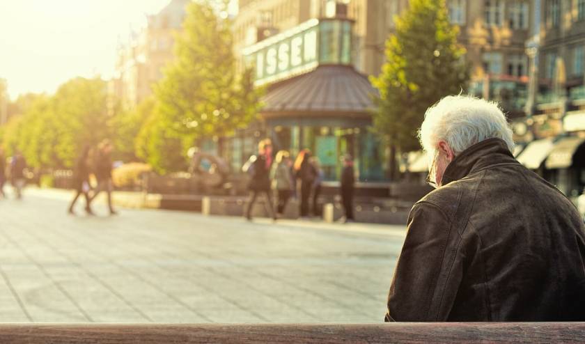 Homme seul assis sur un banc dans la rue, regarde par terre