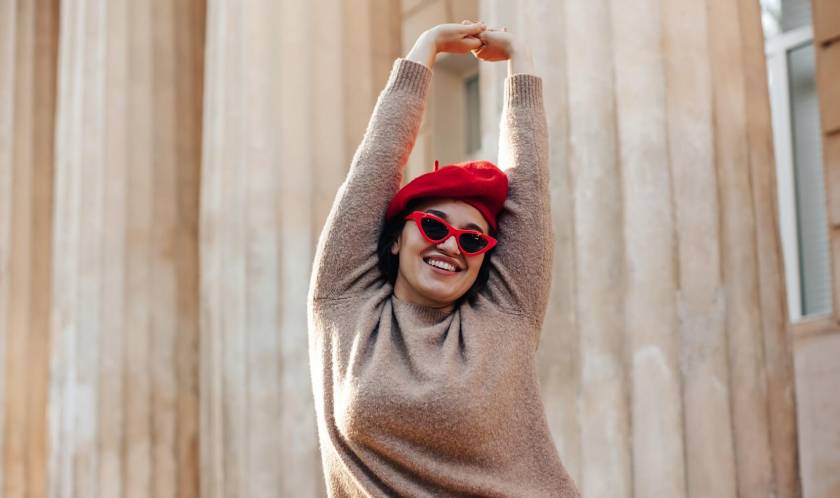 Femme souriante, ronde, avec lunettes de soleil et béret rouge