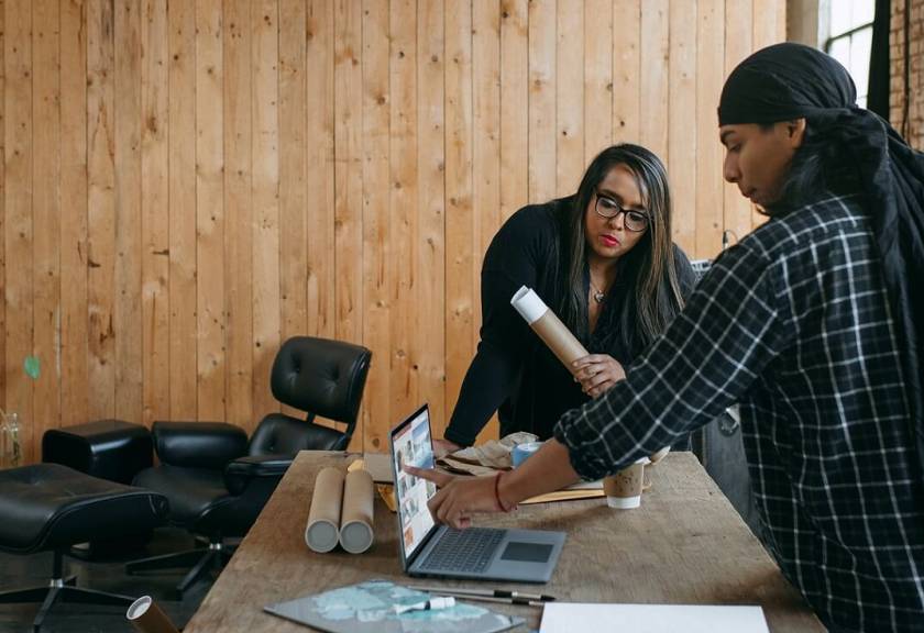 Homme noir avec un foulard, femme noire avec lunettes, parlent dans un atelier