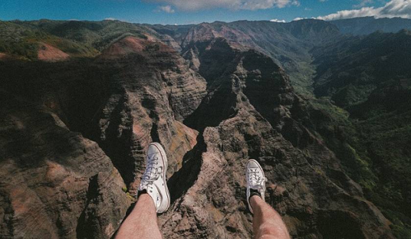 Jambes qui se balançent dans le vide, au-dessus d'un paysage de montagnes