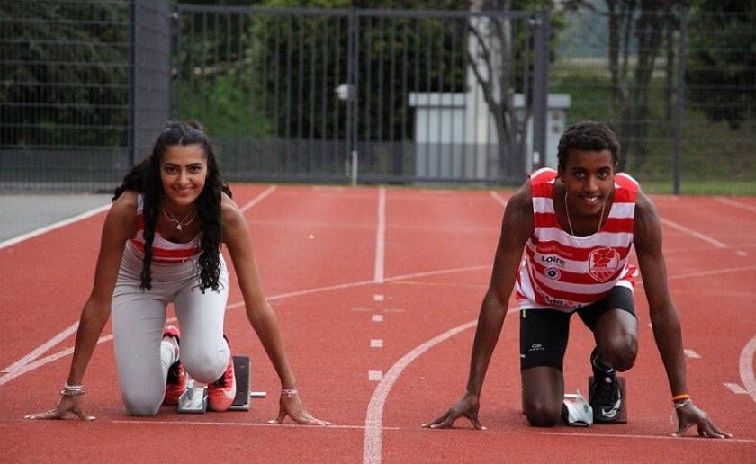 1 femme et 1 homme, maillot rayé rouge et blanc sur piste d'athlétisme