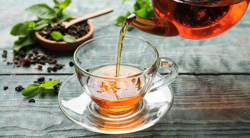 Tasse de thé transparente, théière qui coule, feuilles de menthe