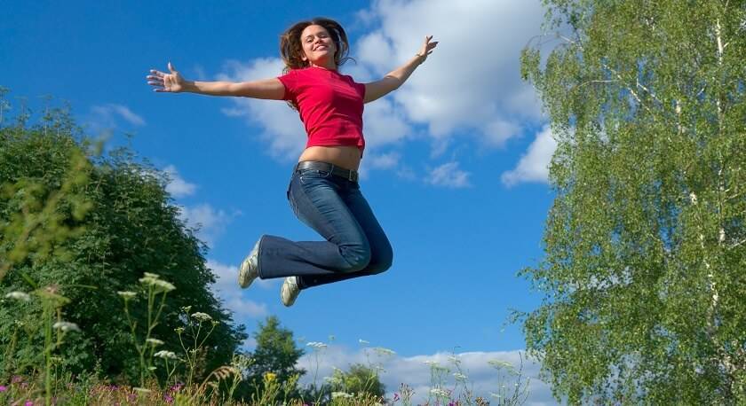 Femme Tshirt rouge saute en l'air, arrière plan campagne