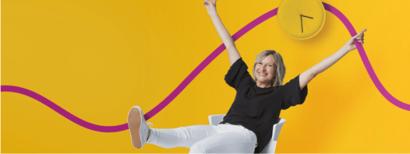 Femme assise sur une chaise qui sourit, pantalon blanc, bras levés, fond jaune