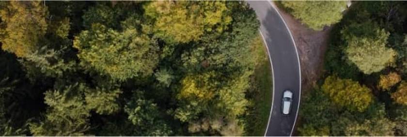 Voiture vue d'en haut, sur une route au milieu d'une forêt