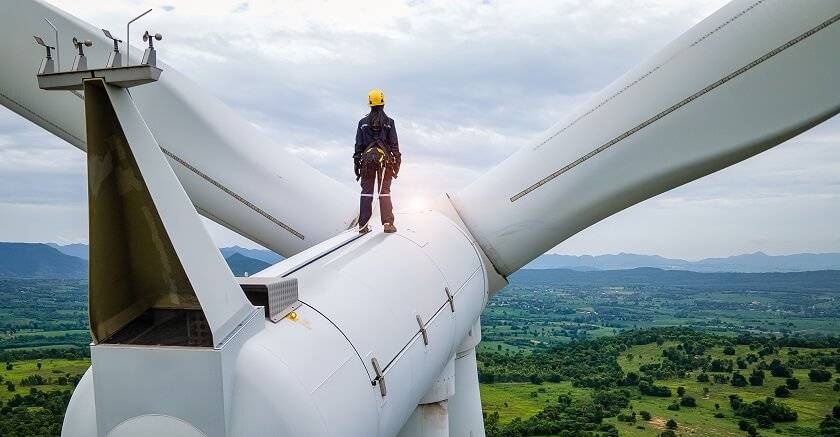 Homme debout sur le haut d'une éolienne