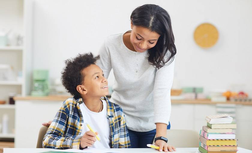 Femme penchée sur enfant avec cahiers et livres