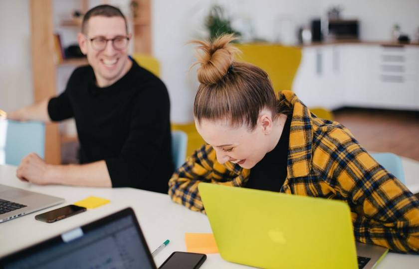 Jeune homme et femme qui rient au travail. Ordinateur jaune