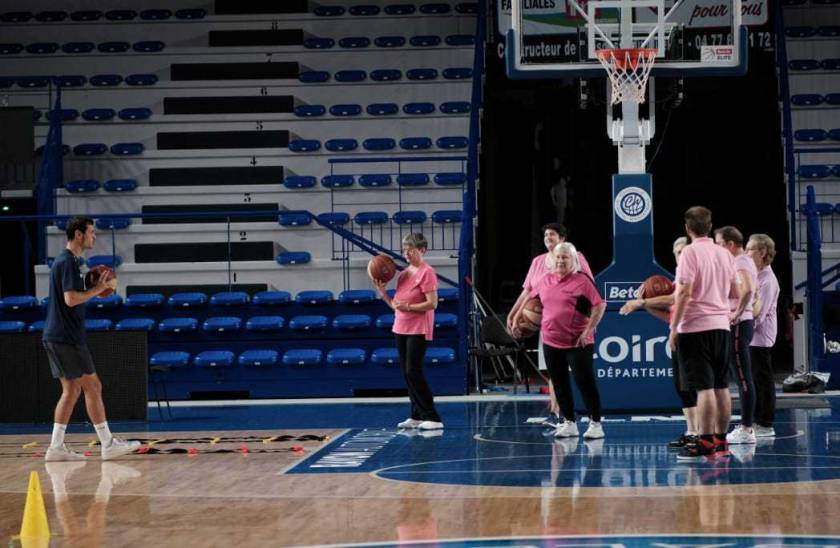 des joueurs de la chorale de Roanne jouent sur un terrain de basket en intérieur