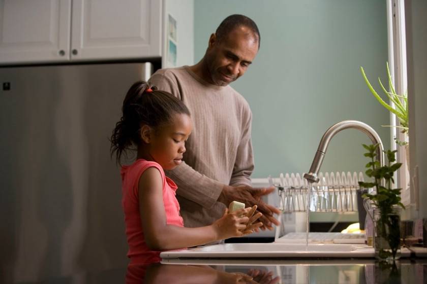 Un père et sa fille se lave les mains dans leur lavabo de la cuisine