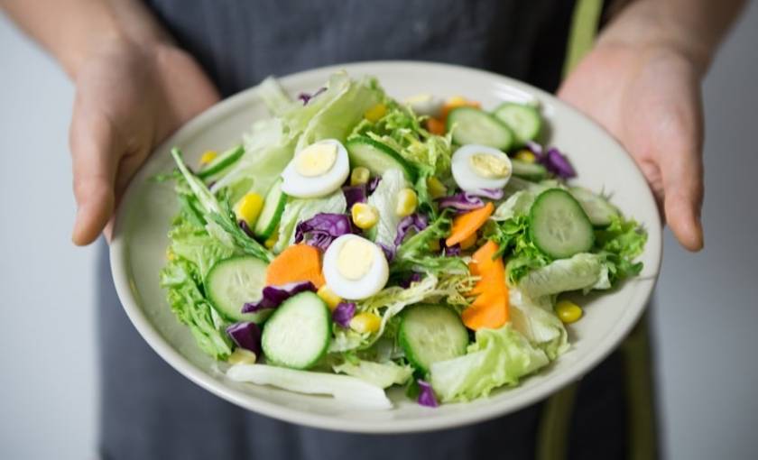 Une personne tient un plat de légumes dans ses mains