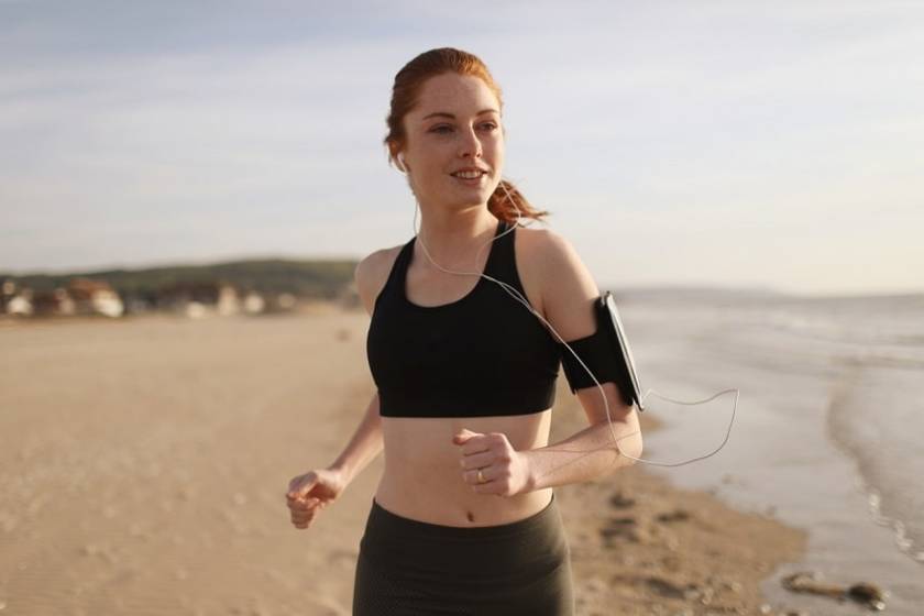 Une fille en tenue de sport court sur la plage