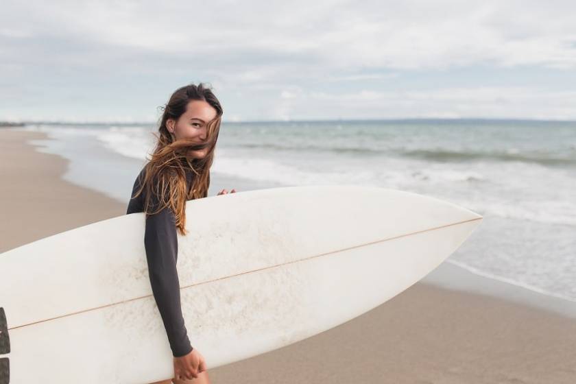 Une femme au bord d'une plage s'apprête à aller surfer 
