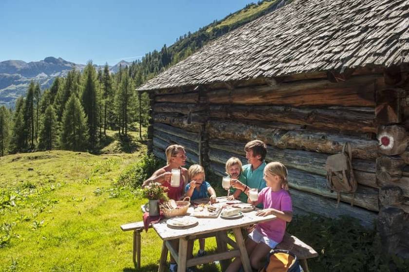 Photo d'une famille mangeant sur une table à côté de leur cabane en montagne