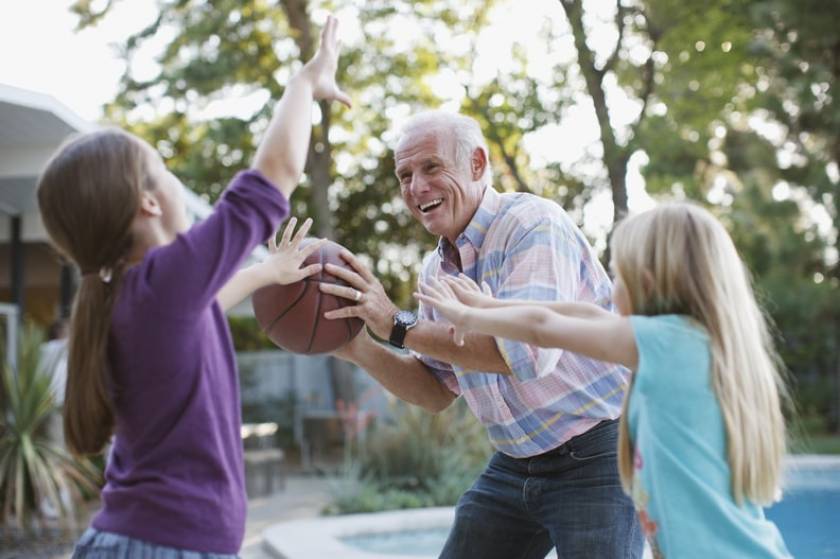 Un senior joue au basketball avec 2 petites filles 