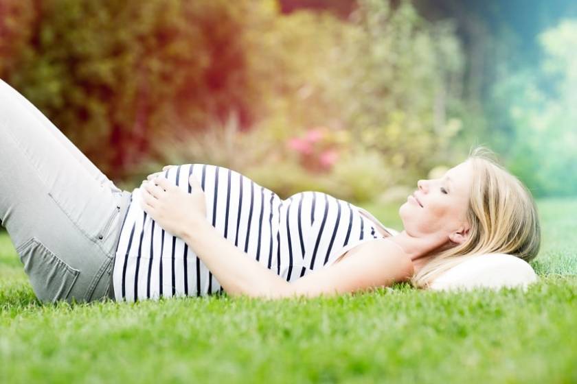 Une femme enceinte se repose dans l'herbe 
