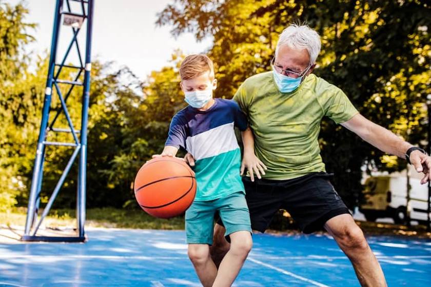 Un enfant et son grand-père jouent au basket à l'extérieur ensemble